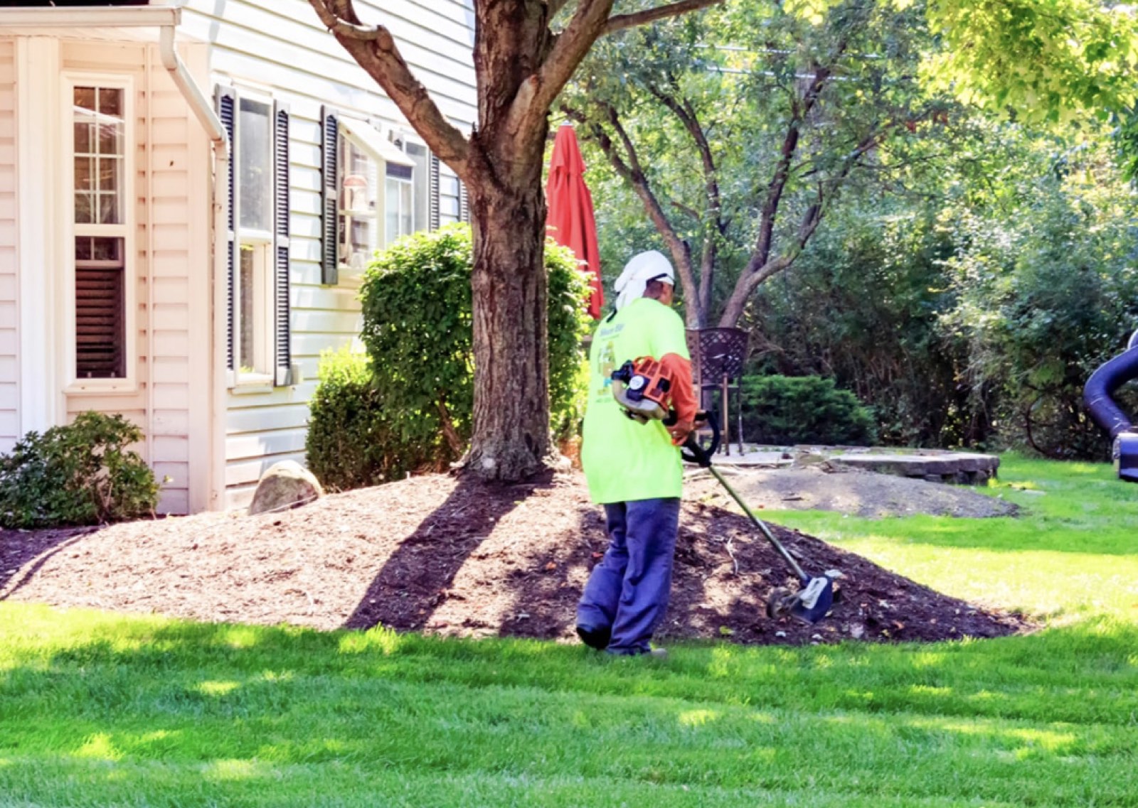 Lawton Lawn and Landscape crew trimming and edging around a mulch bed